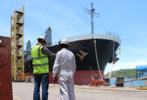 Engineer Workers in a shipyard looking over shipbuilding plans.
