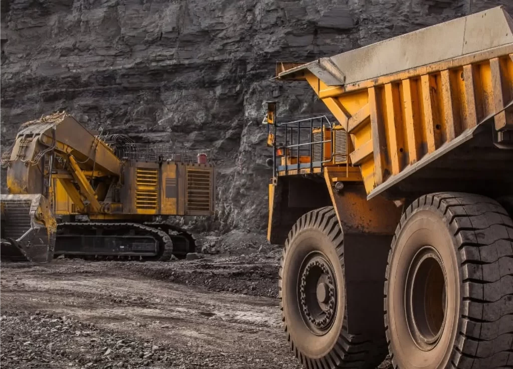 Mining haul truck and excavator in open pit mine — heavy equipment dependent on forged metal components
